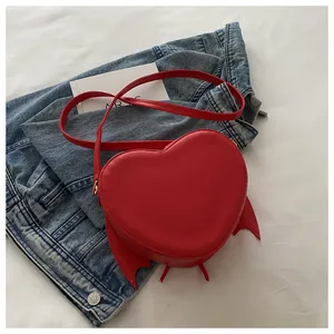 Close-up detail of the red heart-shaped bat wing bag with matching red shoulder strap