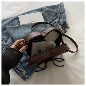 Internal storage detail of heart-shaped dark brown crossbody bag with ribbon design