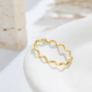 Close-up of a delicate gold wavy band ring with a polished minimalist finish