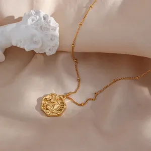 Vista dettagliata della collana con ciondolo tondo dorato con goffratura di fiori di pesco