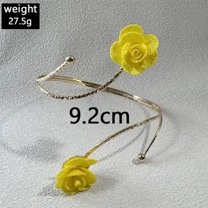 Detailansicht des goldenen Spiral-Armreifs mit zwei lebhaften gelben Stoffrosen für Damen.