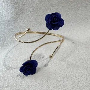 Detailansicht einer eleganten goldenen Armspange mit blauen Stoffblumen für Damen