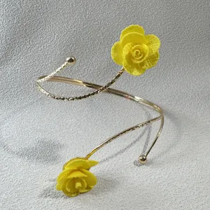 Detailansicht der gelben Stoffrose auf einer goldenen spiralförmigen Oberarmspange