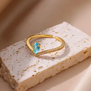 Gros plan sur une bague ajustable en acier doré 18K avec zircon bleu en goutte.