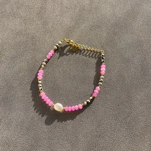 Gros plan d'un bracelet de perles colorées avec cristaux roses et perle d'eau douce.