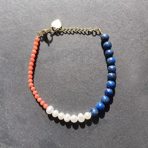 Détail d'un bracelet en perles d'eau douce naturelles avec perles bleues, corail et fermoir cœur