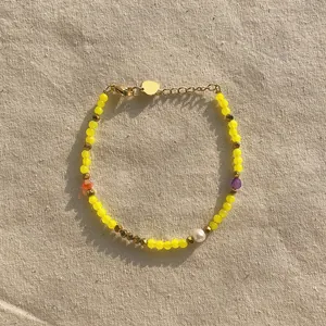 Détail d'un bracelet avec des perles en cristal jaune et une perle d'eau douce naturelle