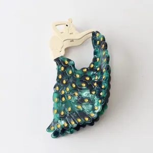 Detailed view of an elegant peacock-shaped acetate hair claw clip with vibrant patterns.