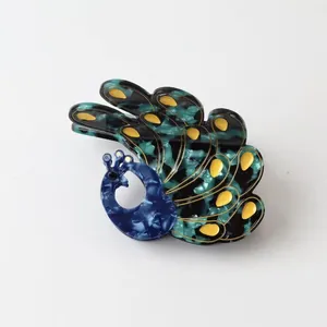 Detailed view of a peacock-shaped hair claw clip made of marbled acetate material.