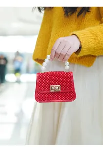 Vista detallada del mini bolso de gelatina rojo con asa de perlas y cierre dorado