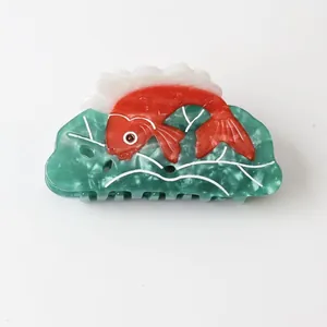 Detailed macro view of vibrant red fish design on green marbled acetate hair claw clip