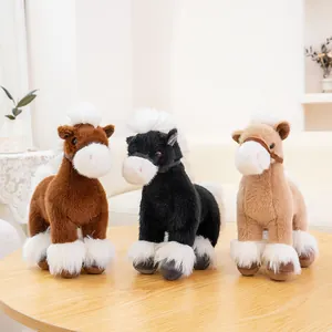 Close-up of three plush toy horses in brown black and tan colors on a wooden table