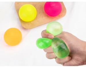 Primer plano de una mano apretando una bola antiestrés de colores para aliviar estrés.