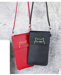 Detailed view of red and black mini crossbody phone bags hanging against a wall