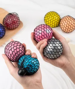 Primer plano de coloridas bolas antiestrés de malla apretadas por una mano humana