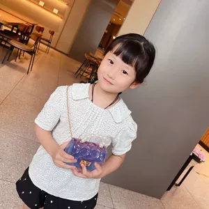 Mini borsa jelly in PVC viola con manico di perle indossata da una bambina modella