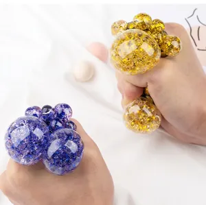 Primer plano de manos apretando pelotas antiestrés brillantes con forma de uva