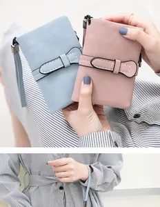 Detail of two soft PU leather wallets in blue and pink held by hand with wrist strap.