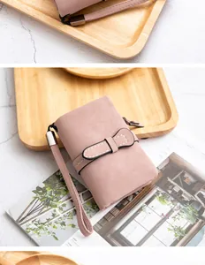Detail of pink soft PU leather foldable women's wallet with wrist strap and bow decoration