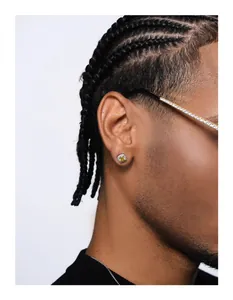 Close-up of a silver iced-out stud earring with yellow stone worn by a model