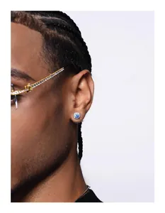 Close-up of a silver hip-hop stud earring with a blue center stone on a male ear.