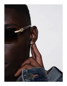 Detail view of a hip-hop silver stud earring featuring a vibrant red gemstone and diamond halo