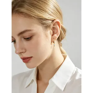 Elegant gold hoop earrings with light blue marquise stone drop on a blonde model.