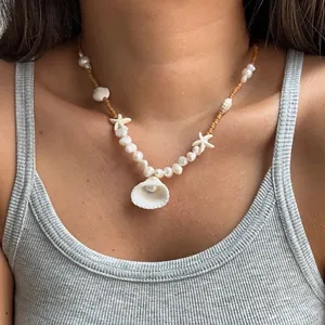 Detail view of a shell and pearl beaded necklace on a model for summer style.