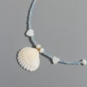 Close-up of beaded necklace featuring natural blue stone, pearls, and shell pendant.