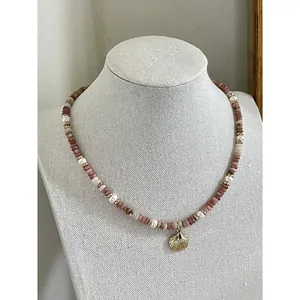 Detailed view of natural stone beaded necklace with pearls and gold shell pendant
