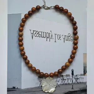 Close-up of summer vacation necklace featuring brown wood beads and a white shell pendant