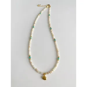 Detailed view of the natural stone and shell bead necklace with a gold shell pendant.