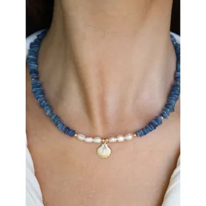 Detailed view of beach-style necklace with blue stones, pearls and shell pendant
