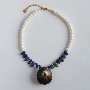 Elegant handmade necklace with white pearls, blue stones, and a large shell pendant
