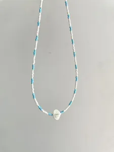 Detail view of summer style blue and white beaded necklace with white shell pendant