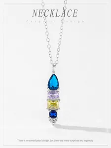 Detail showing a vertical geometric pendant with colorful gemstones on a silver chain