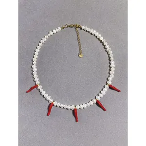 Vue détaillée d'un collier en perles d'eau douce orné de pendentifs en forme de piment rouge.