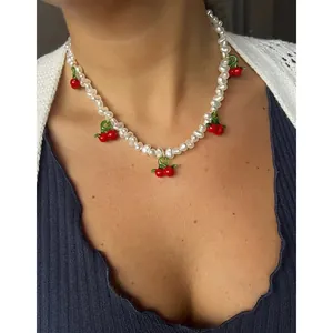 Détail d'un collier en perles d'eau douce avec des pendentifs cerises sur un mannequin