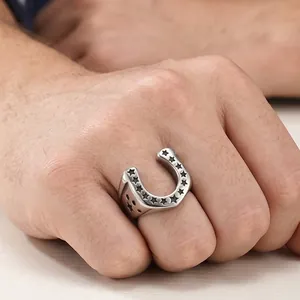 Detailed macro view of men's stainless steel horseshoe ring with star engravings on hand