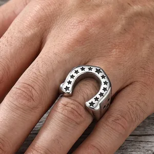 Detailed view of a horseshoe stainless steel ring with black star engraving on a hand.