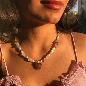 Détail d'un collier fait main avec des perles naturelles et un pendentif raisin en verre.