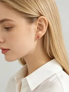 Model wearing a minimalist gold stud earring with a rectangular red zircon stone.