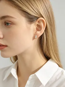 Detailed side view of a minimalist square-cut clear zircon stud earring on ear