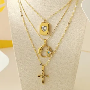 Macro detail view of elegant gold layered necklaces featuring heart moon and cross pendants