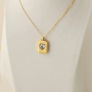 Close-up of gold rectangular pendant necklace with sparkling heart-shaped crystal stone detail.