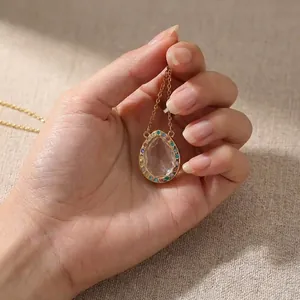 Close-up of a gold-toned openable teardrop photo locket necklace with colorful gems
