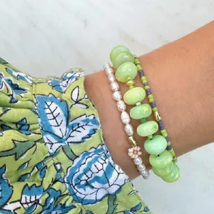 Gros plan de bracelets empilables colorés avec pierres naturelles vertes et perles délicates