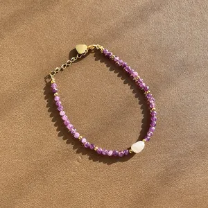 Détail d'un bracelet en perles d'améthyste violette avec une perle baroque blanche au centre