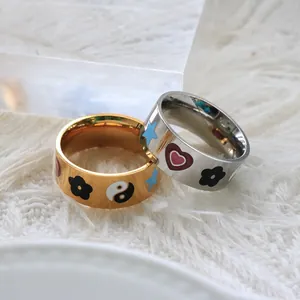 Set di due anelli in smalto colorato con motivi a cuore e fiori in oro e argento