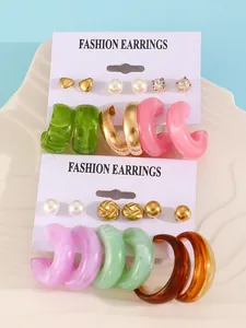 Detail view of colorful resin hoops and gold stud earrings on display cards